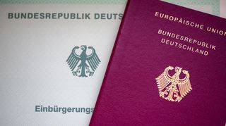 Eine Einbürgerungsurkunde der Bundesrepublik Deutschland (l) und ein deutscher Reisepass liegen auf einem Tisch. Geht es nach Friedrich Merz soll es leichter werden, den deutschen Pass zu entziehen.