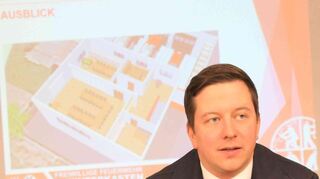 Wehrführer Tobias Pfeifer vor dem Plan des neuen Gerätehauses.
