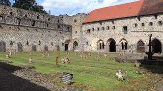 Im Bereich des ehemaligen Kreuzgangs liegt der große Kriegsopferfriedhof, dahinter der Kapitelsaal und links davon die Kirchenruine.