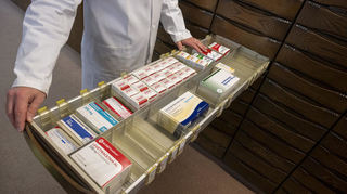 Ein Apotheker schaut in den Medikamentenschrank seiner Apotheke. 2024 mussten nach Angaben der Landesapothekerkammer Baden-Württemberg 70 Apotheken schließen.