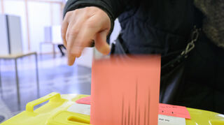 Eine Frau wirft ihren Wahlzettel für die Bundestagswahl 2025 in der Briefwahlstelle im Neuen Rathaus in eine Urne.