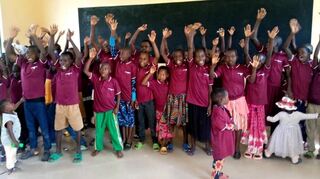 Kinder präsentieren ihre neuen T-Shirts in einem der bereits fertiggestellten Klassenräume am „Ibondo Education Center“ in Tansania.