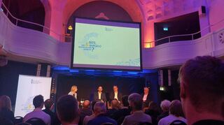 „Bits & Bargeld“-Veranstaltung im Frauenbad Heidelberg: Moderatorin Sissi Hajtmanek (l.), Finanzminister Danyal Bayaz, dm-Manager Martin Dallmeier und Bundesbank-Vorstandsmitglied Burkhard Balz auf dem Podium.