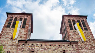 Trauer um Papst Franziskus: Trauerflor an den beiden Fahnen an den Westtürmen der Stadtkirche von Sankt Georg in Bensheim.