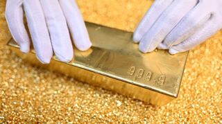 Ein Goldbarren, der 12,5 Kilogramm (400 Unzen) wiegt, einen Feingoldgehalt von 99,99 Prozent hat und auf Goldgranalien liegt.