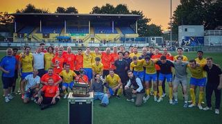 Gruppenbild mit Carl-Rieger-Trophäe: Die Mannschaften des VfR Bürstadt und der Hamburger Victoria im Stadion Hoheluft stellten sich hinter dem Original-Pokal aus dem Fußballmuseum in Dortmund auf.