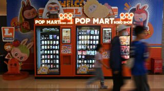 Jugendliche und Kinder gehen an einem Automaten mit Spielzeug-Figuren der Marke Pop Mart in einer Shopping Mall vorbei. +++ dpa-Bildfunk +++