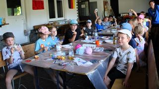 15 Mädchen und Jungen verzierten eine CD mit Glitzersteinen, Federn und bunten Perlen.