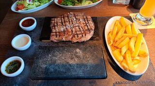 Das Abacco's-Steak liegt beim Servieren auf einem Heißen Stein. Dazu gibt es hausgemachte Pommes und drei Soßen.