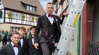 Lukas Mahr erklomm die Leiter zum Alten Rathaus, um nach dem Spruch den Kerwekranz mit Wein zu weihen.