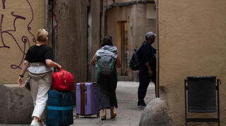 Touristen gehen mit ihrem Gepäck durch die Stadt. Die Stadt Barcelona will bis Ende 2028 Ferienwohnungen abschaffen.