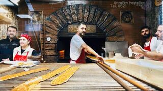 Drei Bäcker arbeiten an dem Ofen, der das Herzstück des Ladens in den G-Quadraten ist.