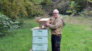 Imker Stefan Hillenbrand füttert die Bienen auf dem Vereinsgelände des Imkervereins 1888 Heppenheim und Umgebung im Erbacher Tal ein. In einen Eimer wird Apiinvert, eine Zuckerlösung, gegossen. Stroh und Weinkorken schwimmen auf der Flüssigkeit. Auf ihnen können die Bienen die Zuckerlösung aufnehmen.