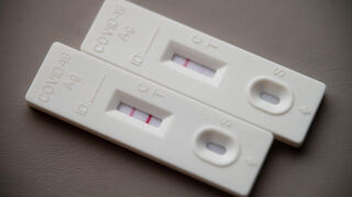 Ein positiver Corona-Schnelltest (l) liegt auf einem Tisch neben einem Corona-Schnelltest, der schwach eine positive Linie hat. Im Kreis Bergstraße steigen die Fallzahlen derzeit moderat an.
