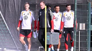 Mit Teamarzt Hahne (2.v.l.) betritt Schlotterbeck (l.) den Trainingsplatz.